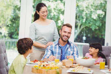 Smiling family with mother standing at dining table