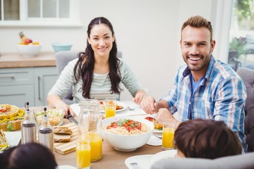 Smiling parents with children sitting at dining table 