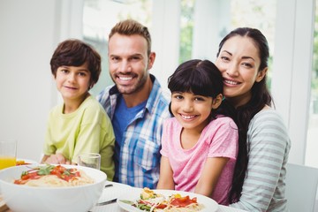 Portrait of smiling parents and siblings at dining table 
