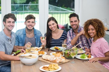 Happy multi-ethnic friends having meal at table
