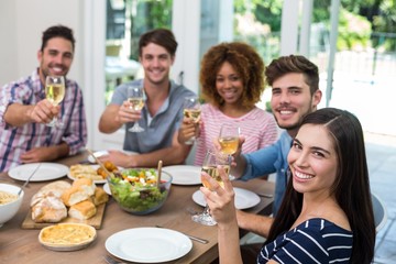 Happy friends showing wine while having meal 