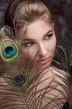 girl with bright  makeup and peacock feathe
