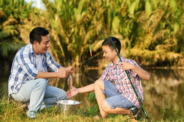 Asian man and teenage boy excited with catch