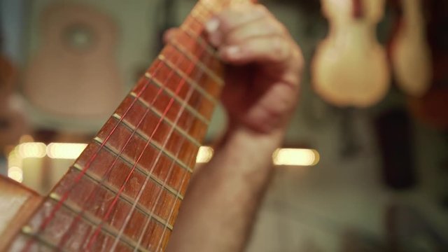 Old people showing love and passion for music. Senior man, elderly person, retired man having fun while playing guitar, musical instrument in lutist workshop. Active retirement, family business