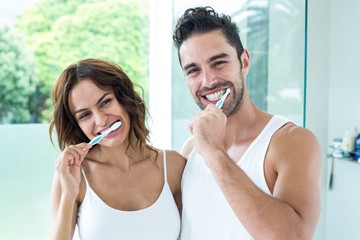 Happy young couple brushing teeth 