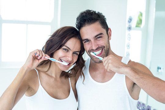 Happy couple brushing teeth in bathroom