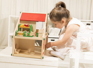 Cute little girl playing with dollhouse. Family house concept - Portrait of little girl with house model. Investment concept for family house. Children imagination or creativity concept