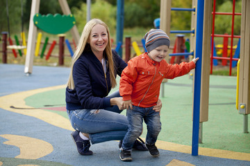 Obraz premium Happy mother and baby boy playing on the playground
