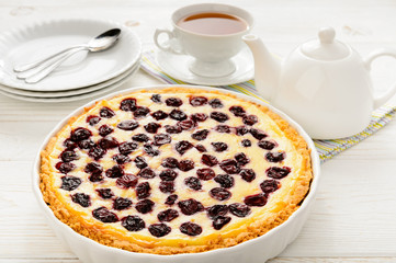 Sweet pie baked with cherries on white wooden table.
