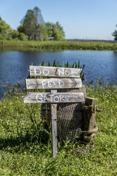 'Do not feed that Gators' wooden sign post, beside a lake in the American deep south