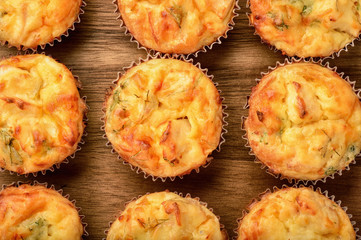 Homemade muffins with chicken and cheese on brown wooden board.
