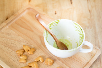 Green tea stains  a cup of coffee and on a wooden tray with a sn