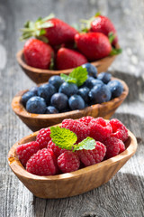 assortment of fresh seasonal berries in a wooden bowl, closeup 