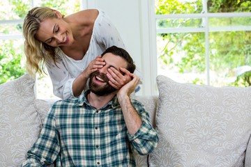 Cheerful wife closing husband eyes from behind