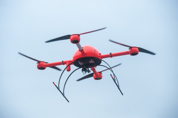 Red industrial drone flies over metal structures industrial faci