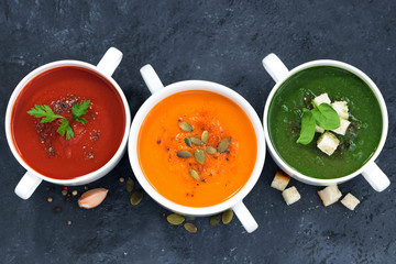 assortment of vegetable cream soup on dark background, top view
