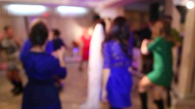 People of different ages are dancing cheerfully at wedding in restaurant . Blurred full hd video clip. Anonymous persons on dance-floor.