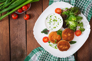 Small chicken cutlet with vegetables on a plate. Top view