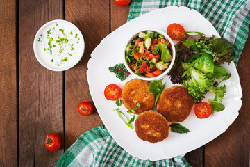 Small chicken cutlet with vegetables on a plate. Top view