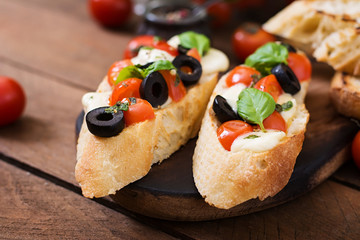 Bruschetta with tomatoes, mozzarella, olives and basil pesto