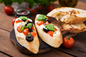 Bruschetta with tomatoes, mozzarella, olives and basil pesto