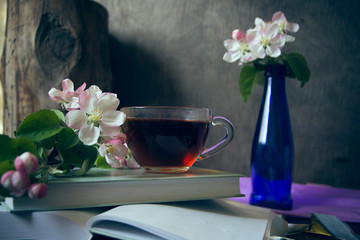cup of tea on book with apple tree blossom branches