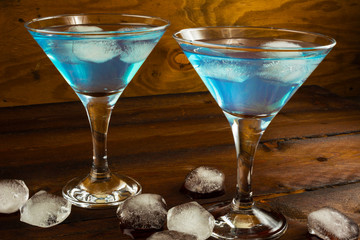 Two blue cocktails in glasses on dark wooden background