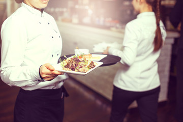 Waiters carrying plates with meat dish at a wedding.