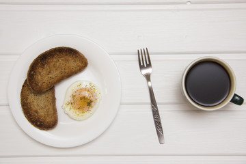 poached egg with two toasts and coffee on rustic background