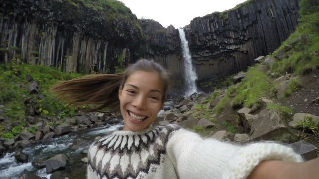Woman enjoying against majestic Svartifoss waterfall. Female is visiting famous tourist attraction of Iceland. She is making faces at spectacular natural landmark on vacation. Skaftafell ACTION CAMERA