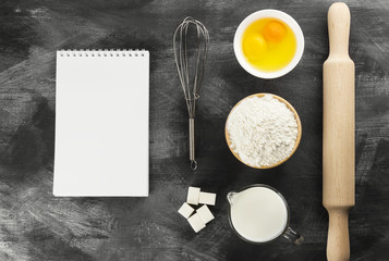 Ingredients for pastries: flour, eggs, milk against a dark backg
