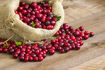 Cranberries in a bag on wooden background.
