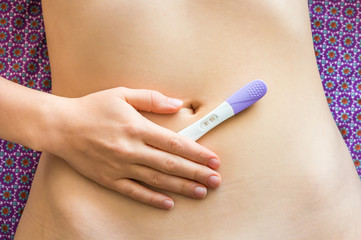 Obraz na płótnie Canvas Pregnant woman holding positive pregnancy test