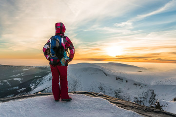 Young girl watching at the sunset on the top of mountains