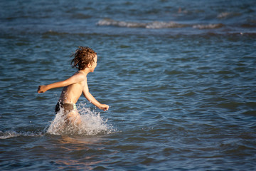 Kleiner Junge läuft durchs Wasser