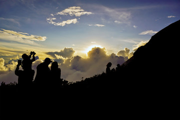 Silhouette of people taking a sunset photo at mountain
