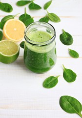 Glass jar of fresh summery drink green smoothie, spinach leaves, lime fruit. Vertical.