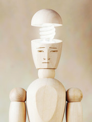 Glowing light bulb in the human head. Concept of genius. Abstract image with wooden puppet