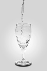 
Pouring water into wine glass on white background