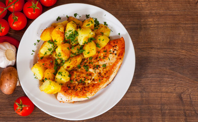 Grilled chicken breast with potato in a plate on wooden table