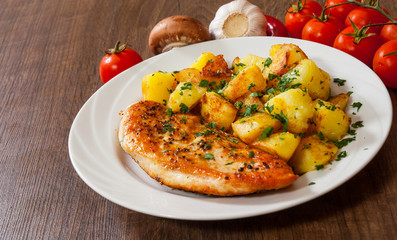 Grilled chicken breast with potato in a plate on wooden table