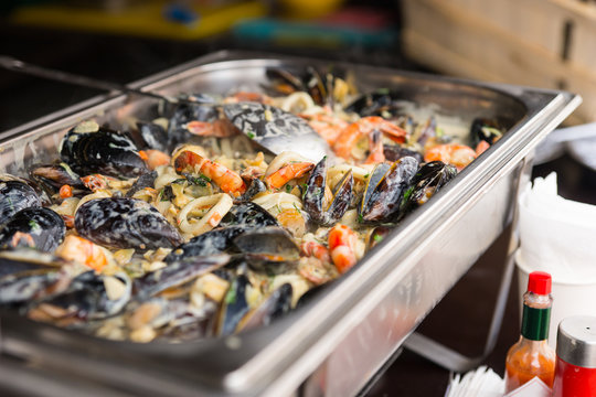 Mussels and seafood in a large metal catering dish