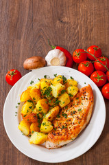 Grilled chicken breast with potato in a plate on wooden table