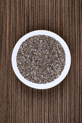 Chia seeds on white porcelain plate, wood background table.