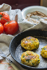 Healthy vegetarian patties made from potatoes, carrots, onions, and green on a background of tomato sauce, selective focus.