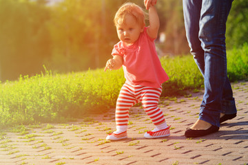 Naklejka premium first steps of little girl in summer park