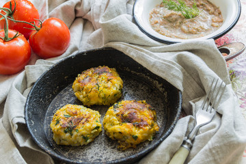Healthy vegetarian patties made from potatoes, carrots, onions, and green on a background of tomato sauce, selective focus.