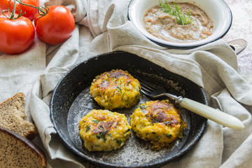 Healthy vegetarian patties made from potatoes, carrots, onions, and green on a background of tomato sauce, selective focus.