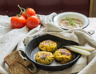 Healthy vegetarian patties made from potatoes, carrots, onions, and green on a background of tomato sauce, selective focus.