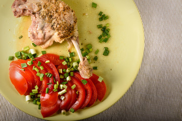 Утка тушенная с аппетитными помидорами и зелёным луком на тарелке